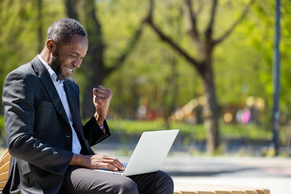 Un étudiant sourit devant son ordinateur portable pendant une session de cours à distance